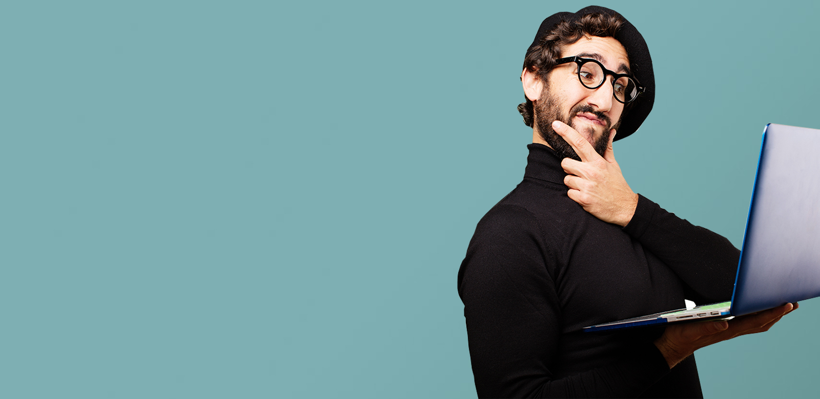 uomo che pensa con un computer portatile in mano con uno sfondo verde acqua vestito di nero